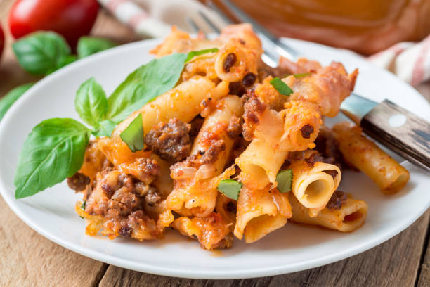 Ziti bolognese on white plate, pasta casserole with minced meat, tomato sauce and cheese, horizontal stock photo