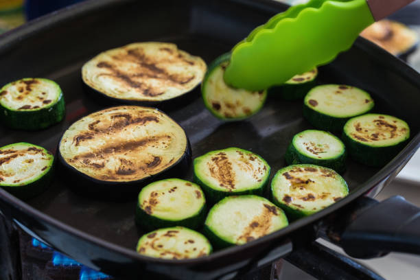 zucchini, cucumber and eggplant frying in non stick pan stock photo