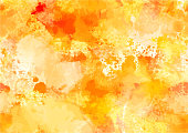 An abstract watercolour autumn background with yellow and orange brush strokes and splashes of paint