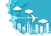 Vector layered paper cut style sky, fluffy clouds, plane flying over city buildings. Worldwide travel, air flight, time to travel concept for web banner, website page etc.