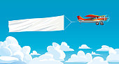 istock Aircraft red with ribbon banner advertising, in the sky above the clouds. Vector 1291836275