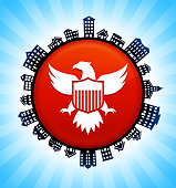 American Eagle and Shield  on Rural Cityscape Skyline Background. The button is in the center of the illustration. a detailed 100% vector rural cityscape skyline is placed around the circumference of the button and includes various houses, single family homes, residential condominium and other suburb buildings. There is a blue sky background with a star burst glow rendered behind the buildings. The image is ideal for displaying rural suburban life concepts and ideas.