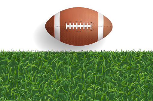 American football ball on green grass texture background.