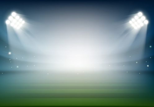 Blank football field on the stadium. Sports background illuminated by searchlights.
