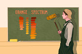 Boy in an art class standing in front of the blackboard and learning the spectrum of orange color