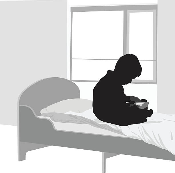 Boy's Quiet Time A vector silhouette illustration of a young boy sitting on his bed  alone in his bedroom playing a handheld game. bedroom silhouettes stock illustrations