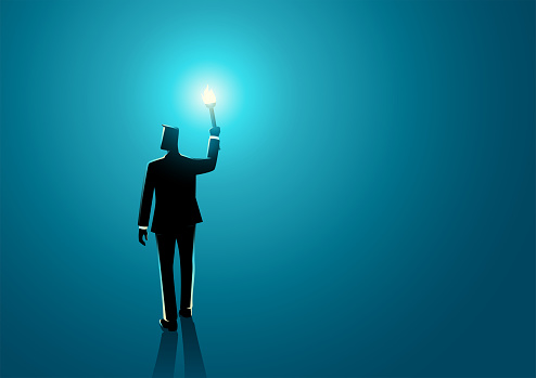 Businessman walking in the dark holding a torch