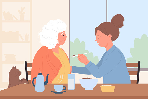 Care and help for elder people from volunteers, young caregiver feeding senior woman