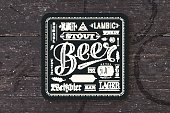 Coaster for beer with hand drawn lettering. Monochrome vintage drawing for bar, pub and beer themes. Black square for placing a beer mug or a beer bottle over it with lettering for beer theme. Vector Illustration