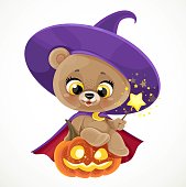 Cute teddy bear sitting on a halloween pumpkin with magic wand isolated on a white background