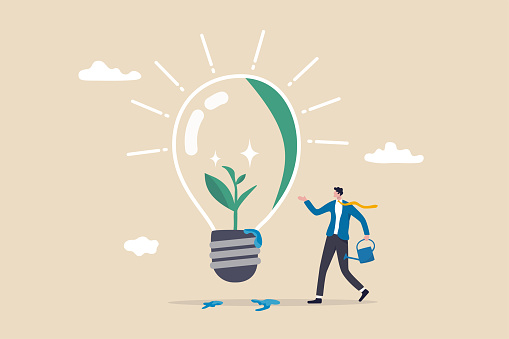 Ecology and sustainable business, green idea or protection against world climate change, environmental care concept, smart businessman watering seedling sprout growing inside green lightbulb idea.