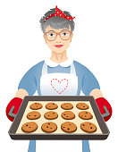 Elderly woman holding a baking sheet with chocolate cookies isolated on a white background.
