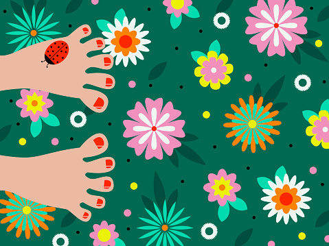 feet with painted nails and a ladybug on bright green grass with colorful flowers