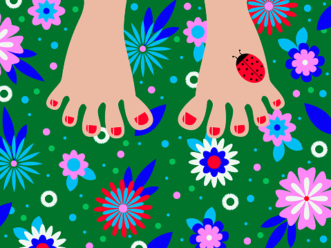 feet with painted nails on bright green grass with decorative multicolored flowers