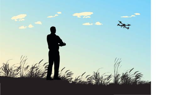 Flight Hobby A vector silhouette illustration of an adult man playing with a remote controlled flying drone in a field with wind blown reeds and against a blue sky. drone silhouettes stock illustrations