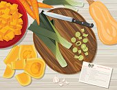 Flat lay of foods and cooking utensils on a wood background. Assorted vegetables and cutting board.