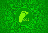 CO2 Footprint Environment Green Vector Icon Pattern. The main icon depicted in this royalty free vector illustration is in the center of the composition and is green in color.  It is surrounded by environmental conservation icons that vary in size and shade of color. These nature and environment icons form a seamless pattern and fill the entire background of the image. The background has a dark green color. Each icon can also be used independently of the icon pattern. Vector icons include such elements as nature, recycling, people and trees and many more.