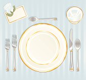 China, silverware, glass and place card with rose on a blue tablecloth.