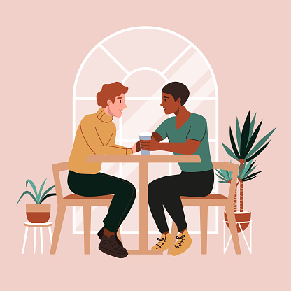 Gay couple on a date at cafe. First date or valentines day. Romantic scene with lgbt family, marriage. Two men drinking coffee, talking and smiling, holding hands.