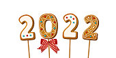 istock Gingerbread cookie numerals on sticks with phrase 2022 in cartoon style. Sweet biscuit in new year message with red bow isolated on white background. Vector illustration 1352099116