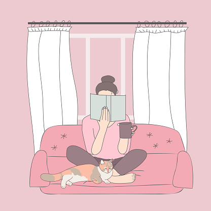 Girl sitting at home on the couch with book and cat