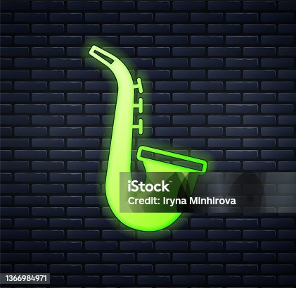 istock Glowing neon Musical instrument saxophone icon isolated on brick wall background. Vector 1366984971