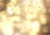 Gold confetti and streamers on a defocussed background