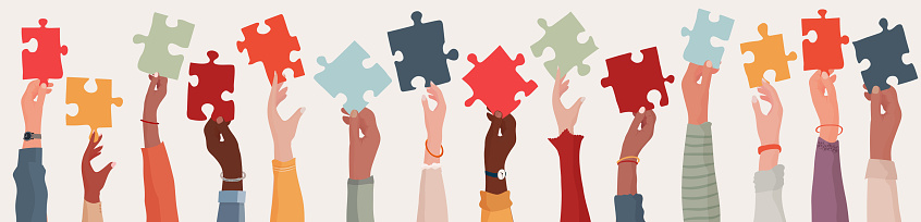 Group of multi-ethnic business people with raised arms holding a piece of jigsaw. Colleagues of diverse races and culture. Cooperate and collaborate. Concept of teamwork and success
