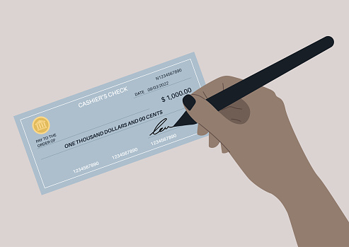 A hand signing a bank paper check, financial operations