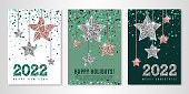 Happy Holidays banners set of three sheets with shimmer hanging stars, emerald confetti and 2022 numbers. Vector flyer design templates for greeting cards. All layered and isolated