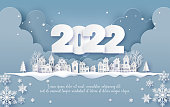 "nMerry Christmas and Happy New Year 2022 , Countryside Village in winter paper collage and paper cut style with digital craft ."n