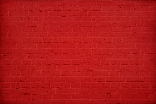 A dark bold red colored brick wall with rectangular blocks, textured grungy backgrounds. No text. No people, copy space, copyspace.  The masonry joints joint are red in color.  Xmas, Christmas theme backgrounds
