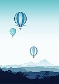 Vintage hot air balloons over blue smoky mountains landscape.