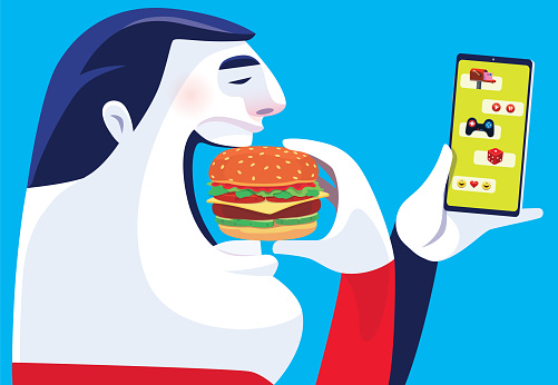 man eating hamburger and checking smartphone