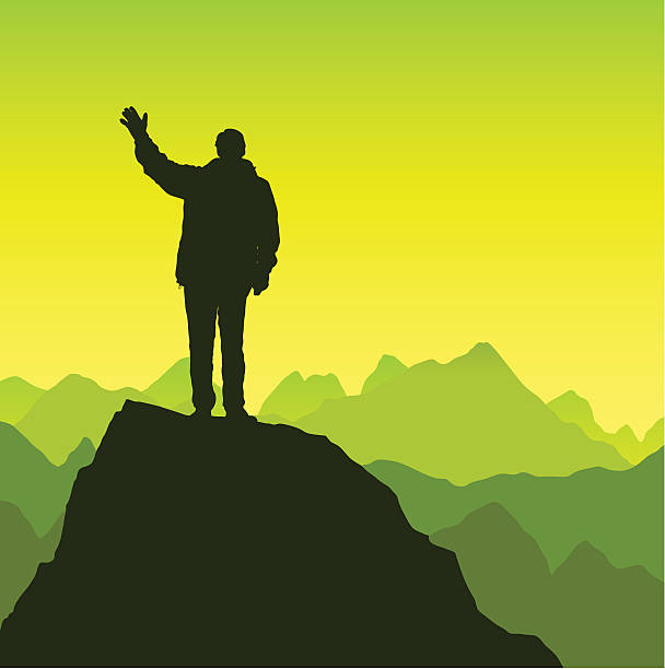 A man waves on top of a mountain.