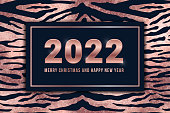 2022 Merry Christmas and Happy New Year greeting card design with shiny rose gold numbers and pink foil tiger pattern background. Vector illustration for web, xmas banner, mail, flyer.