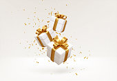 istock Merry New Year and Merry Christmas 2022 white gift boxes with golden bows and gold sequins confetti on white background. Gift boxes flying and falling. Vector illustration 1332102612