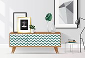 Wooden sideboard with plants and posters on it against white wall. Modern interior with tropical elements and geometric patterns. Vector illustration