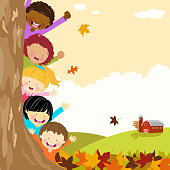 Kids hiding behind autumn tree.