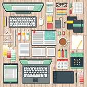 An overhead view of items you might find on the desk of a graphic designer, including: Laptop, tablet, smart phone, computer, sketchbooks, color swatches, paints, pencils, pens, coffee, design books, calendar, drawing tablet, backup hard drive, USB Flash drives, rulers, and so on. No gradients or transparencies used. File is organized into layers and each icon is properly grouped for easy editing.