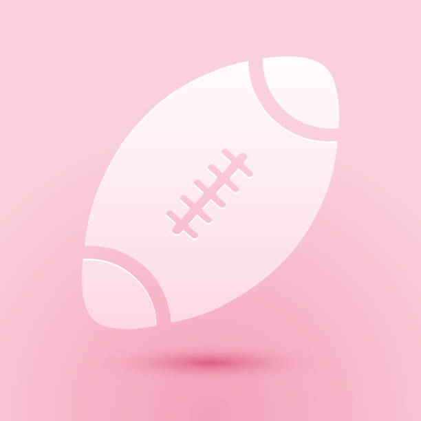 Paper cut American Football ball icon isolated on pink background. Paper art style. Vector Paper cut American Football ball icon isolated on pink background. Paper art style. Vector. pink soccer balls stock illustrations