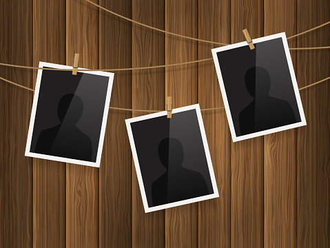 Photo frames fixed on the rope with clothespins on wood background. Vector.