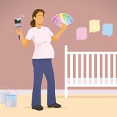 Pregnant women holding paint brush and colour swatches choosing colours for her babies nursery.