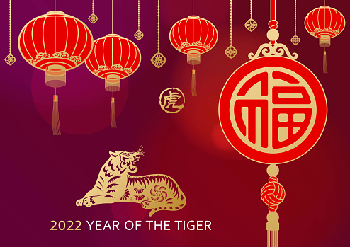 Celebrate the Chinese New Year in the year of the Tiger 2022 with gold colored papercutting tiger, decoration of lanterns, pendants and good luck charm hanging on the red background,  the Chinese stamp means tiger