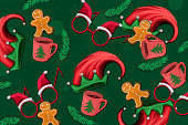 Illustrated pattern of red Santa Clause hat, gingerbread cookies and a cup of hot cocoa on green background