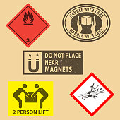 istock Set of fragile sticker handle with care and case icon packaging symbols sign, Do Not Place Near Magnets, Flammable liquids, Explosives  rubber stamp on cardboard background. Use on package. 1391537026