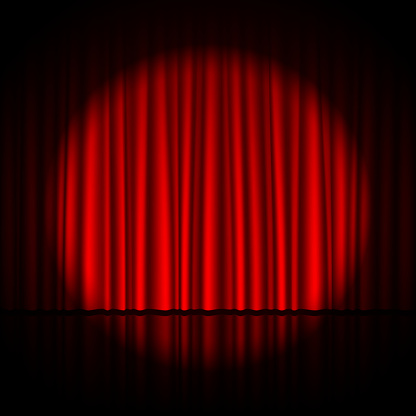 Single spotlight shining on pleated red theatrical curtains
