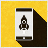 istock Smartphone with rocket. Icon with long shadow on textured yellow background 1397324504