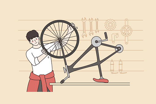 Smiling man repair bicycle in small workshop