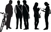 A vector silhouette illustration of students socializing after class.  A group of three young men engage in conversation while one man stands by his bike and another two men wear shoulder bags.  Two young women exchange information entering information from a notebook into a smart phone.